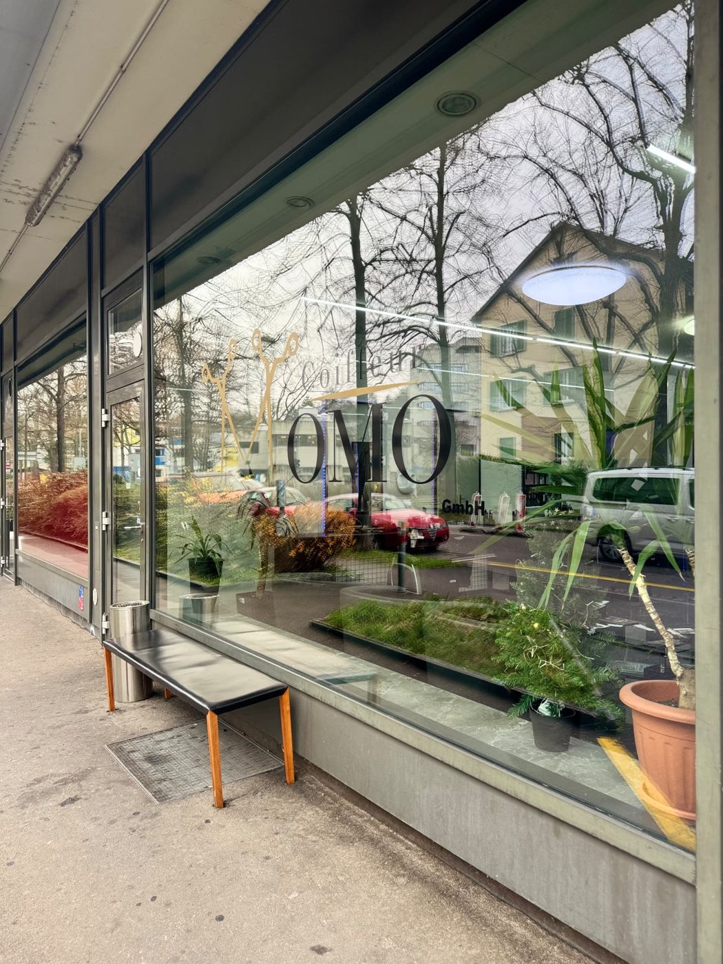 Schaufenster von Coiffeur Momo mit goldenem Logo in Basel